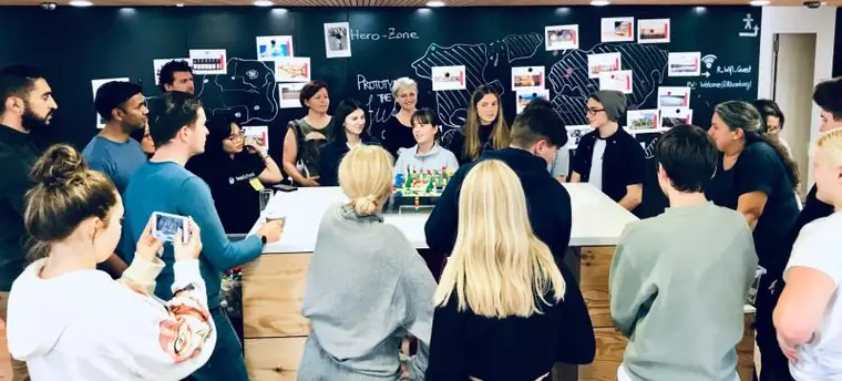 Group standing around a table with a prototype in front of a blackboard wall