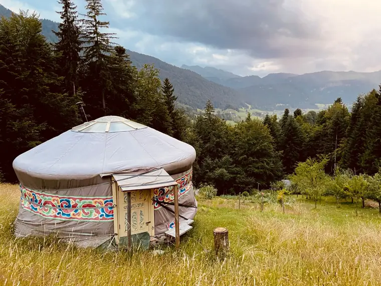 A yurt in a mountain meadow at the edge of the forest
