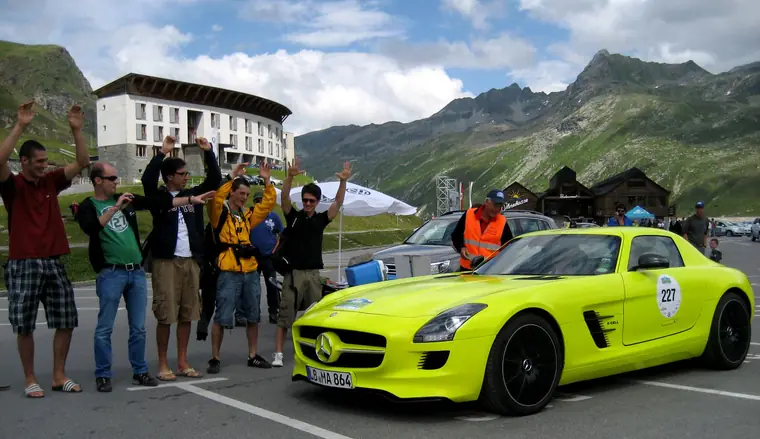 Cheering group next to a yellow-green electric sports car at the Silvretta e-car rally